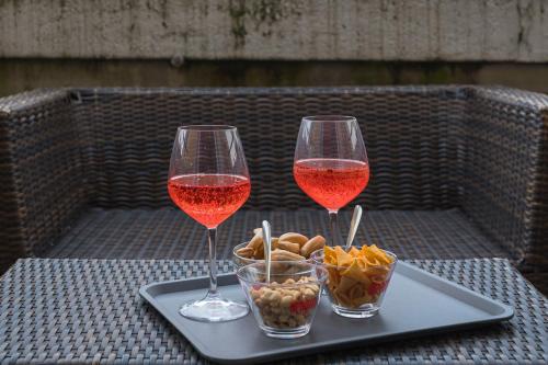 two glasses of wine sitting on a tray with snacks at Hotel Bogart Milano in Milan
