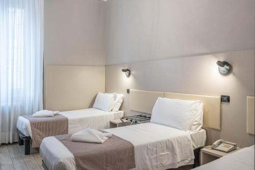 a hotel room with two beds and a phone at Hotel Bogart Milano in Milan