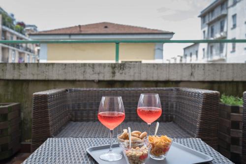 two glasses of wine sitting on a table with snacks at Hotel Bogart Milano in Milan