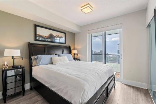a bedroom with a large bed and a large window at 3BR Skyline Condo - By CN Tower & MTCC & Free Parking in Toronto