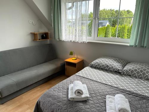 a bedroom with a bed and a couch and a window at DW Róża Wiatrów in Dębki