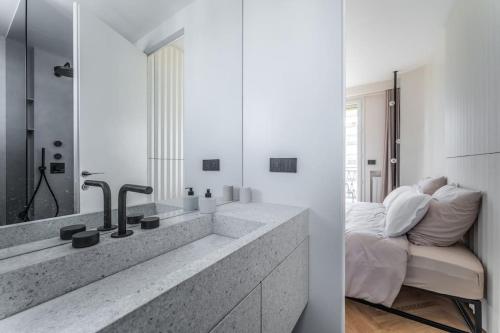 - deux vues sur une salle de bains pourvue d'un lavabo et d'un miroir dans l'établissement Luxueux Appartement Haussmannien avec Vue sur Paris, à Paris