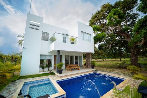 une maison blanche avec une piscine devant dans l'établissement Cabaña Villa July, à Moñitos