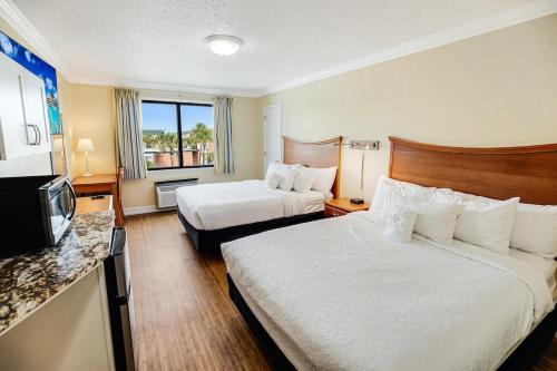 une chambre d'hôtel avec deux lits et une télévision dans l'établissement Beach Bound 3rd Floor Resort View Lodge Room, à Pawleys Island