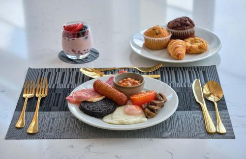 two plates of breakfast food on a table with forks and spoons at Muthu Oban Regent Hotel in Oban