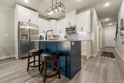 a kitchen with white cabinets and a sink and stools at The Rose Retreat - Walk to the Broken Arrow Rose District in Broken Arrow