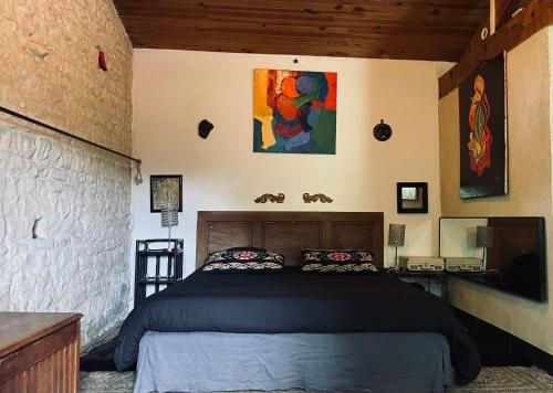 ein Schlafzimmer mit einem Bett und einem Gemälde an der Wand in der Unterkunft Dormir Ben Aise Hammam Massages in Maillezais