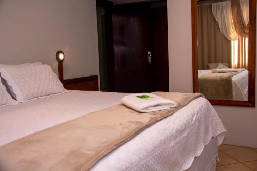 a white towel is on the end of a bed at HOTEL DOMHOF in Blumenau