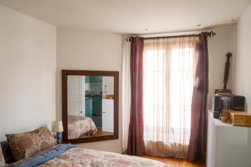 - une chambre avec un miroir, un lit et une fenêtre dans l'établissement Chaleureux appartement parisien, à Paris