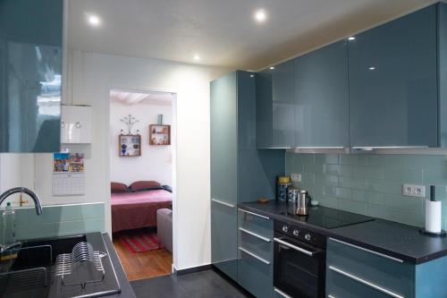 - une cuisine avec des placards bleus et un lit dans une chambre dans l'établissement Chaleureux appartement parisien, à Paris