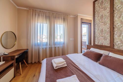 1 dormitorio con 1 cama grande, escritorio y ventana en Kragujevac center apartments, en Kragujevac