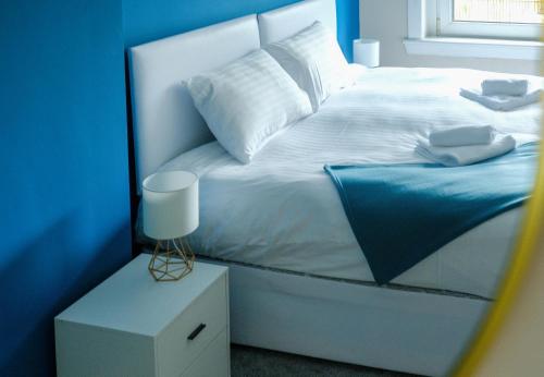a bedroom with a white bed with a blue wall at Register House Family or Contractor 4bed with Garden Driveway in Bellshill
