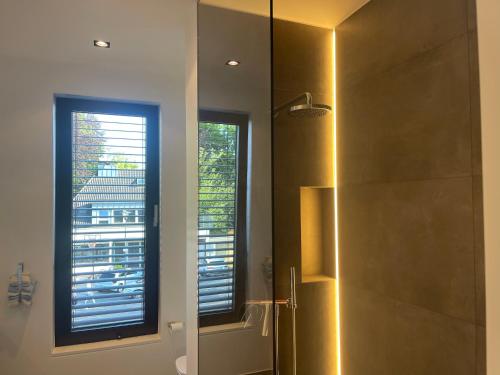 a bathroom with a shower with a mirror and a window at Zum EM Stadion zu Fuß - Luxus im Grünen in Cologne