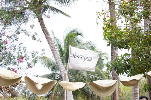 a sign hanging from a palm tree with hats at Kibayo Lagoon Villa in Cabarete