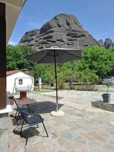 a patio with a table and a chair and an umbrella at Paradise of Meteora A in Kastrákion