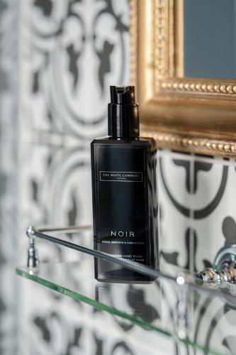 a bottle of perfume on a glass table in front of a mirror at St Martins Lodge in Leicester
