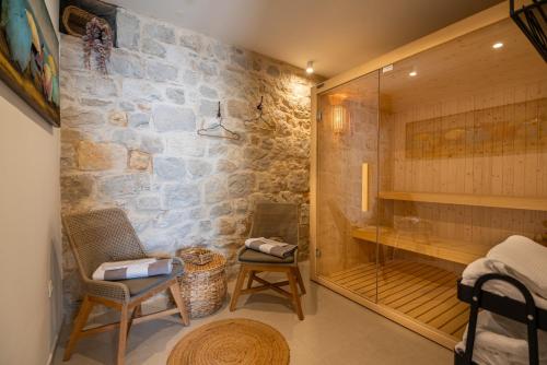 a bathroom with a walk in shower and two chairs at Villa Bella Vista Heritage Oasis in Podstrana