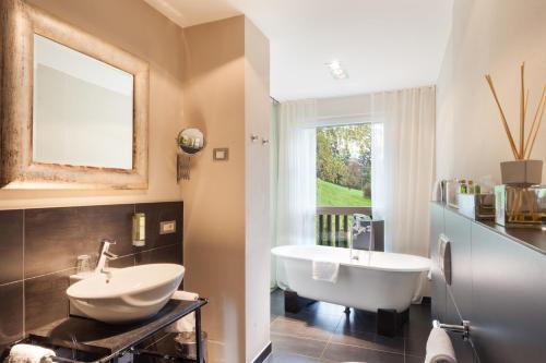 a bathroom with a sink and a tub and a mirror at Hotel KÜGLERHOF in Tirolo