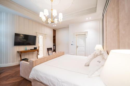 a bedroom with a large white bed and a chandelier at La Fe Boutique Hotel Sarande in Sarandë