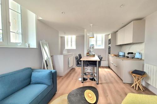 un salon avec un canapé bleu et une cuisine dans l'établissement Bright duplex with magnificent sea views, à Saint-Malo