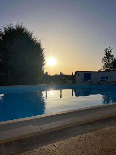 a swimming pool with the sunset in the background at Moinhos do Paneiro in Santiago do Cacém