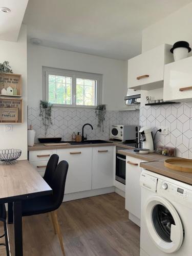 une cuisine avec des armoires blanches, une table et un évier dans l'établissement La Bonne Alt 303m, à Céret