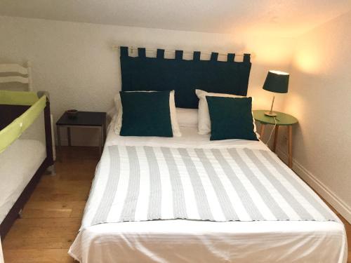 une chambre avec un grand lit blanc avec des oreillers verts dans l'établissement Les portes de la Plage, à Port-Leucate