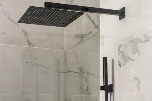 a shower with white marble walls and a black shower head at Denver Emerald - Close to Red Rocks, Arvada & Downtown in Denver