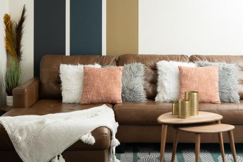 a living room with a brown couch with pillows at Denver Emerald - Close to Red Rocks, Arvada & Downtown in Denver