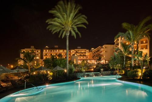 a swimming pool with a palm tree and buildings at Vincci Selección La Plantación del Sur in Adeje