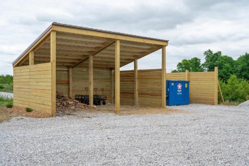 a large woodenshed with a blue recycling container at Block of 4 Lodges at Eden Reserve - For Groups in Williamstown