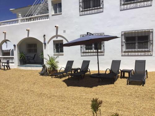 a group of chairs and an umbrella in front of a building at Cortijo Los Corazones in Cantoria