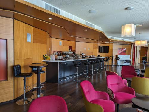 a bar in a restaurant with pink chairs at Le M & Spa Bordeaux Aéroport by Hôtels & Préférence in Mérignac