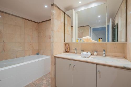 une salle de bain avec deux lavabos, une baignoire et un miroir dans l'établissement Veeve - Safari Glade, à Paris