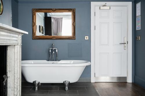 a bath tub in a blue bathroom with a mirror at St Martins Lodge in Leicester