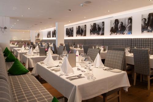 ein Restaurant mit weißen Tischen und Stühlen und Bildern an der Wand in der Unterkunft Kräuter & Spa-Hotel Das Schäfer - Adults only in Fontanella