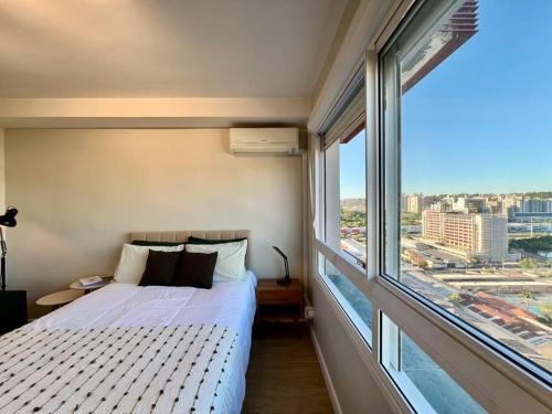 ein Schlafzimmer mit einem Bett und einem großen Fenster in der Unterkunft Terraço, Aconchegante, Gym, Ar, WiFi, PUCRS, Pet in Porto Alegre