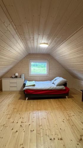 a bed in a room with a wooden floor at Domki Magdalenka in Kamień