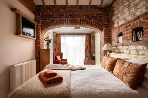 Un dormitorio con una cama grande y una pared de ladrillo. en The Roost, Heritage Escapes, Field House Farm, en Bempton