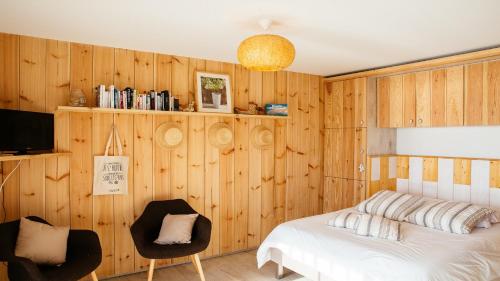- une chambre avec des murs en bois, un lit et des chaises dans l'établissement Cabane bois bord de l'eau, à Gujan-Mestras