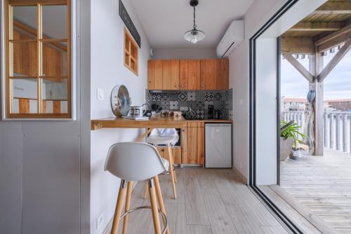 - une cuisine avec des murs blancs, des placards en bois et des tabourets dans l'établissement Cabane bois bord de l'eau, à Gujan-Mestras