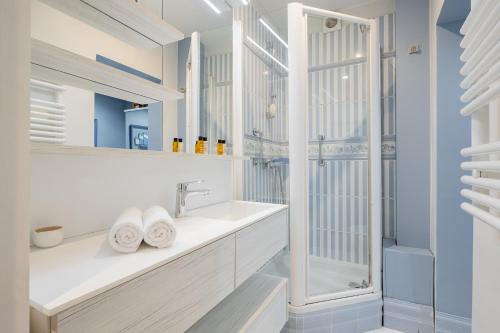 une salle de bain blanche avec un lavabo et une douche dans l'établissement Veeve - Triumphant Design, à Paris