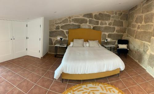 a bedroom with a bed and a stone wall at Casa 1921 in Quinés