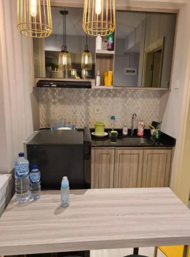 a kitchen with a table with water bottles on it at Apartemen Benson Studio Plus in Surabaya
