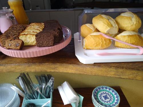 a table with a tray of bread and pastries at Pousada Prumirim Surf Suítes in Ubatuba