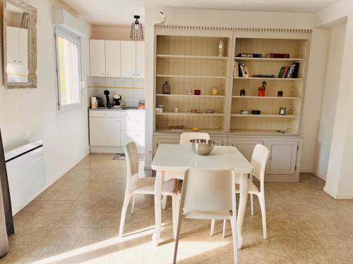 une cuisine blanche avec une table et des chaises blanches dans l'établissement Appartement T2 Avignon proche remparts BALCON et PARKING, à Avignon