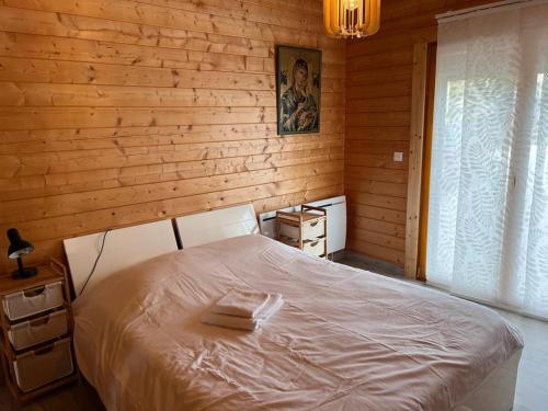 - une chambre avec un lit blanc et un mur en bois dans l'établissement Chalet près de la rivière, à Urzy
