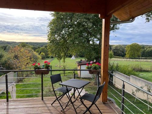 une table et des chaises sur une terrasse avec vue sur un champ dans l'établissement Chalet près de la rivière, à Urzy