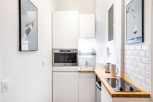 une cuisine blanche avec des armoires blanches et un évier dans l'établissement GuestReady - Beautiful Getaway near Eiffel Tower, à Paris