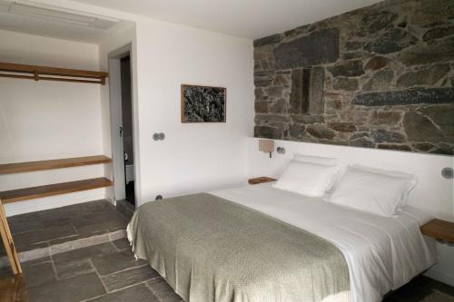 a bedroom with a bed and a stone wall at FLH Douro Casa do Mártir in Vila Marim
